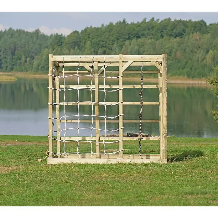 Kinderspielturm Kubisch Zeta - L x B x H: 225 x 185 x 210 cm - Ein Holzklettergerüst mit Seilnetz und Strickleiter steht auf einer grünen Wiese, im Hintergrund ein See und Bäume.