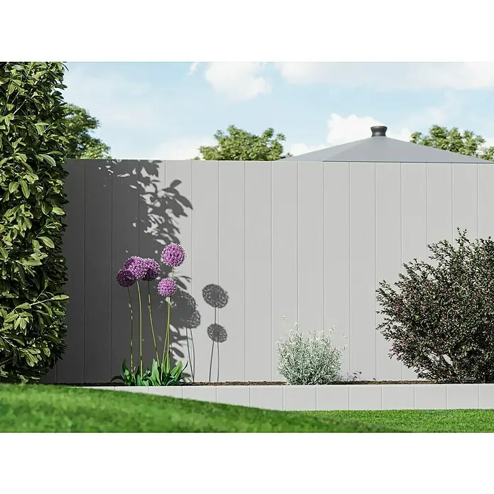 Diephaus Rechteckpalisade - 16,5 x 12 x 200 cm, Grau, Beton - Eine graue Zaunanlage mit lila Blumen und grünen Pflanzen im Garten, die eine friedliche und gepflegte Atmosphäre vermittelt.