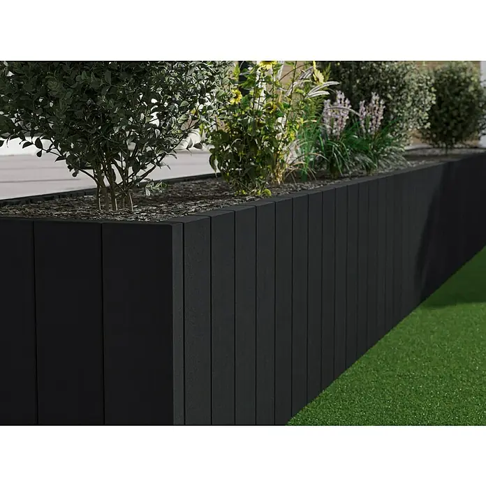 Diephaus Rechteckpalisade Mini - Anthrazit, 8 x 20 x 120 cm, Beton - Bildunterschrift: Eine erhöhte schwarze Pflanzkiste mit Pflanzen. Die Pflanzkiste besteht aus vertikalen Brettern und hat eine steinige Füllung.