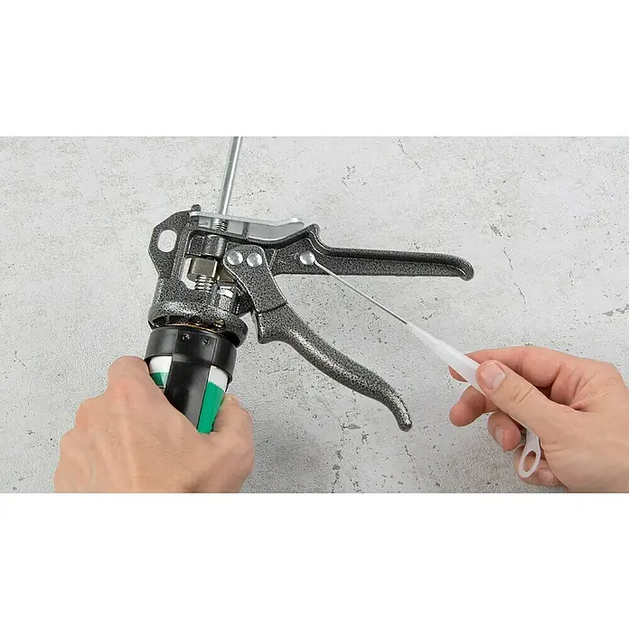 Wisent Kartuschenpresse Profi Qualität - Geeignet für: Verbundmörtel - Eine Kartuschenpistole mit einem weißen Reinigungsstift vor einem grauen Hintergrund, bereit für Handwerks- oder Bauprojekte.