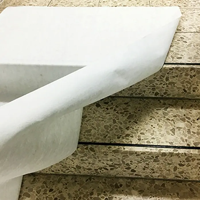 Universal-Vlies10 x 0,5 m - Nahaufnahme einer weißen Papierrolle auf einer Treppe mit Terrazzoboden, ideal für den Schutz bei Malerarbeiten.