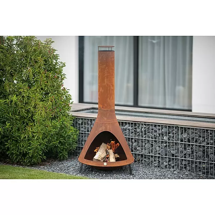Westmann Feuerstelle - 70 x 70 x 160 cm, Metall, Rost - Rostfarbener Cortenstahl-Kamin (Chimenea) mit brennendem Feuer, im Garten auf Kies stehend.