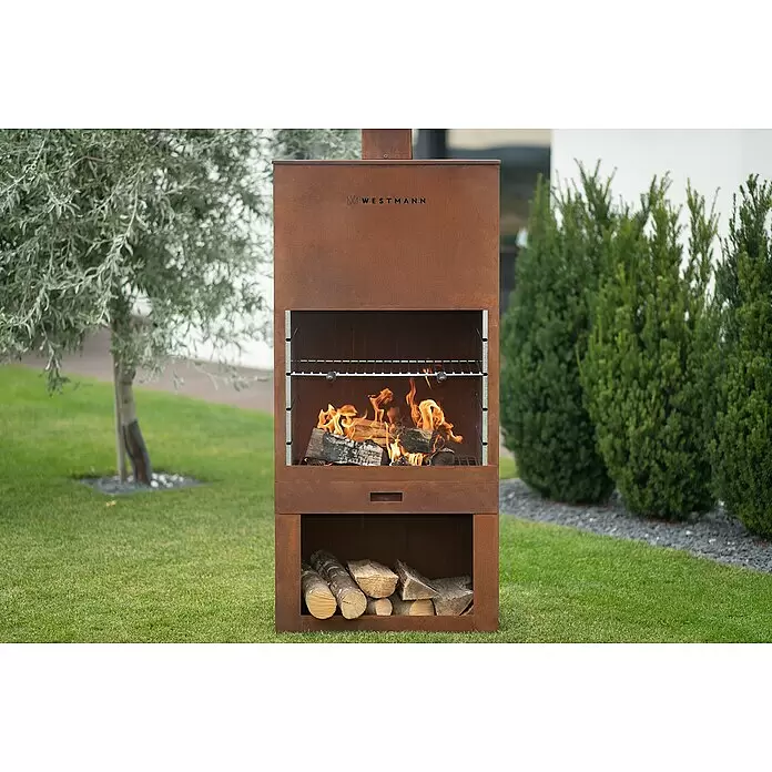 Westmann Grillkamin - L x B x H: 410 x 700 x 2.290 mm, Rost, Stahl - Großer Outdoor-Grill aus rostbraunem Cortenstahl mit brennendem Feuer und Holzlager.