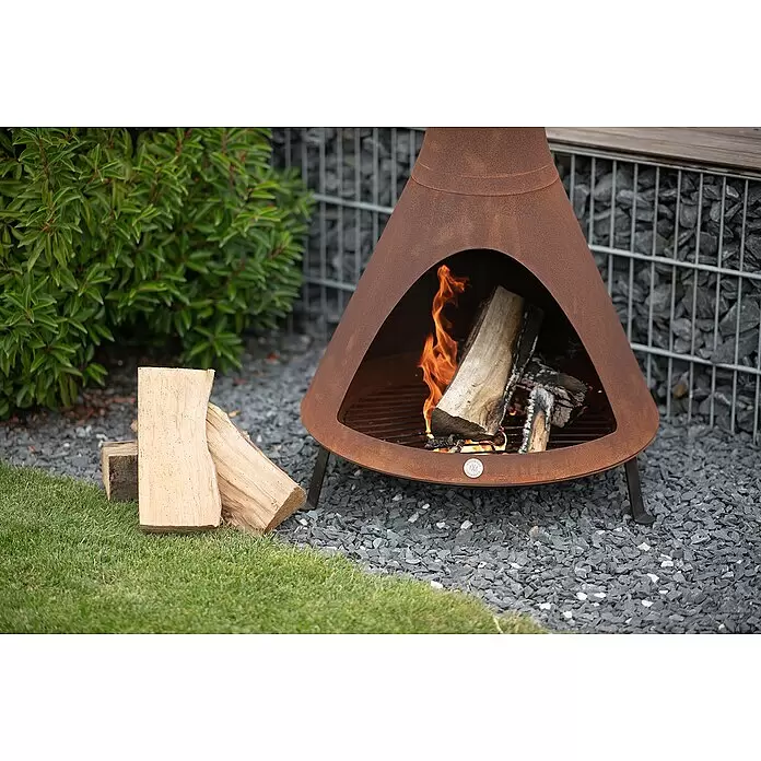 Westmann Feuerstelle - 70 x 70 x 160 cm, Metall, Rost - Rostfarbene konische Feuerschale mit brennenden Holzscheiten auf grauem Kies im Garten.