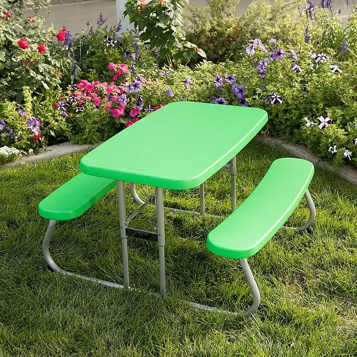 Lifetime Kinder-Picknicktisch - L x B x H: 83 x 90 x 54 cm, Polypropylen, Grün - Ein grüner Kindertisch mit Bänken steht auf einer Wiese vor einem Blumenbeet. Perfekt für Picknicks und Spiele im Freien.