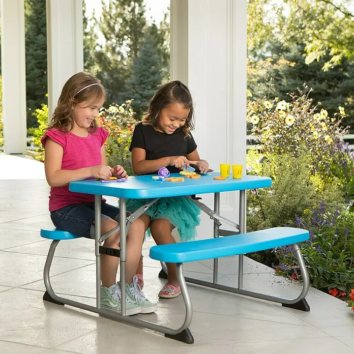 Lifetime Kinder-Picknicktisch - L x B x H: 83 x 90 x 54 cm, Polypropylen, Blau - Ein blauer Kindertisch mit zwei Mädchen, die daran sitzen und spielen. Der Tisch hat integrierte Bänke und steht auf einer Veranda.
