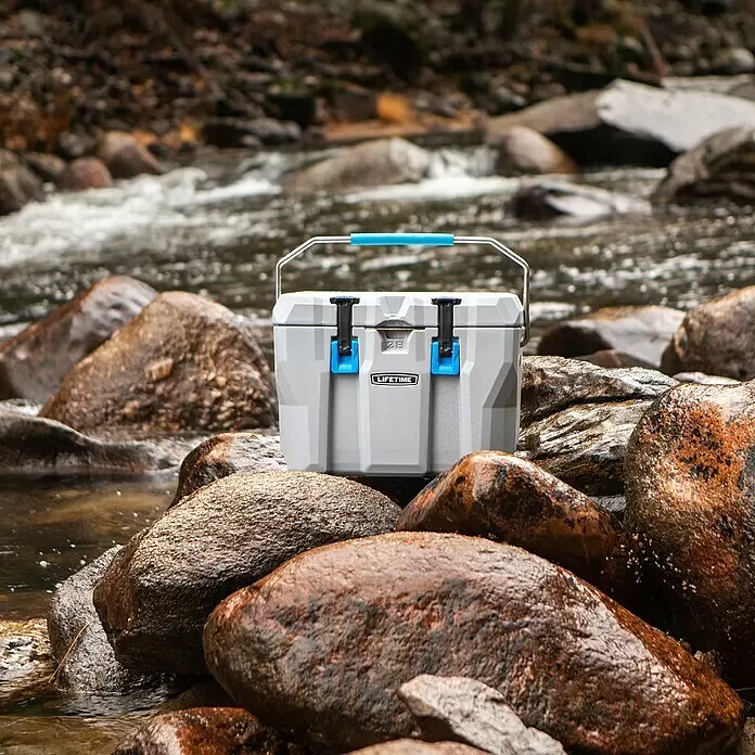Lifetime Kühlbox Cooler - 26,5 l, Grau/Blau - Graue Lifetime 28 Kühlbox mit blauem Griff und Verschlüssen, auf nassen Steinen am Fluss.