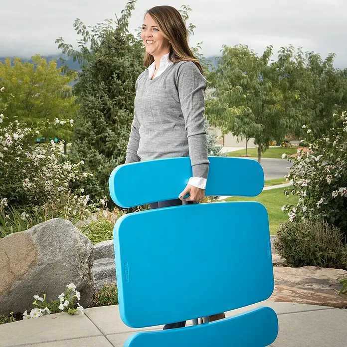 Lifetime Kinder-Picknicktisch - L x B x H: 83 x 90 x 54 cm, Polypropylen, Blau - Eine Frau trägt einen zusammenklappbaren, blauen Picknicktisch der Marke Lifetime im Freien.