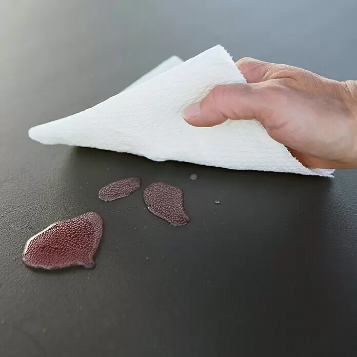 Lifetime Auflagenbox - 573 x 1.525 x 67 cm, Kunststoff, Anthrazit - Hand wischt roten Flüssigkeitsfleck mit weißem, texturiertem Papiertuch auf.
