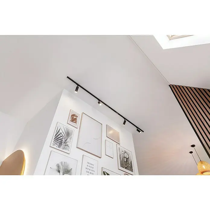 SCHÖNER WOHNEN-Farbe Wandfarbe Designfarbe - Leichtes Leinenbeige, Matt, 2,5 l, Konservierungsmittelfrei - Ein modernes Interieur mit Fokus auf einer schwarzen Stromschienenleuchte, die die Bildergalerie an der Wand beleuchtet.