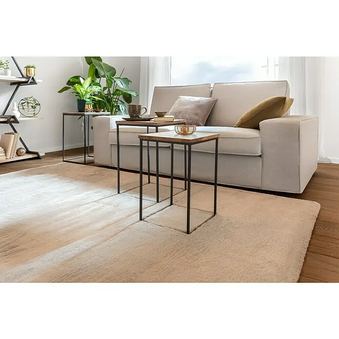 Fellteppich Happy - Elfenbein, 290 x 200 cm, 100 % Polyester (Flor) - Wohnzimmer-Szene mit einem beigen Sofa, einem flauschigen Teppich und zwei Beistelltischen mit Holzplatte und schwarzem Metallgestell.