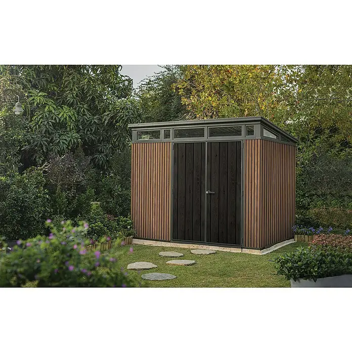Keter Gerätehaus Signature Venetian Pent 9x7 - Außenmaß inkl. Dachüberstand (B x T): 277 x 218 cm, Kunststoff, Braun, 6 m² - Gartenszene mit modernem Gartenhaus. Das Gartenhaus hat eine Holzverkleidung und eine dunkle Doppeltür mit einem silbernen Griff.