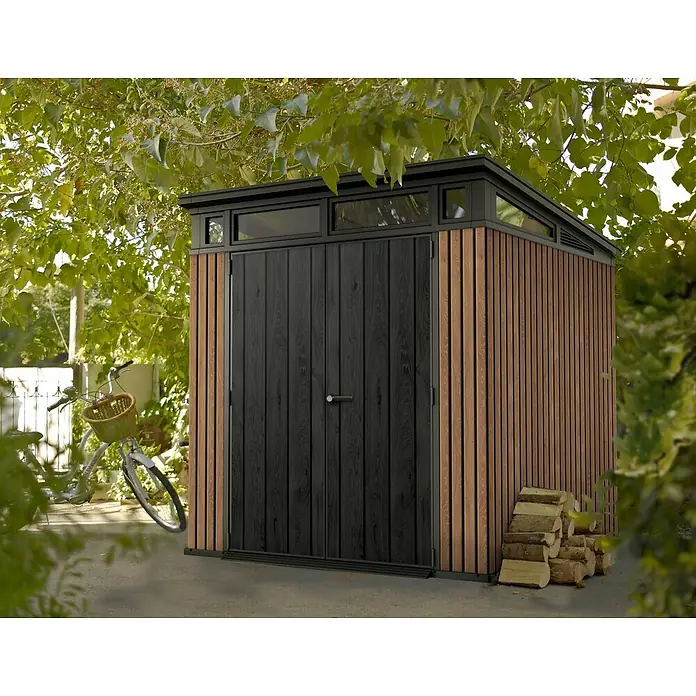Keter Gerätehaus Signature Venetian Pent 7x7 - Außenmaß inkl. Dachüberstand (B x T): 216 x 218 cm, Kunststoff, Braun, 4,66 m² - Ein modernes Gartenhaus mit schwarzen Türen und Holzpaneelen steht im Garten, umgeben von Grün.