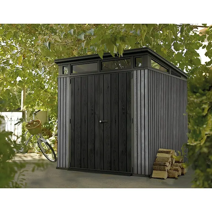 Keter Gerätehaus Signature Venetian Pent 7x7Außenmaß inkl. Dachüberstand (B x T): 216 x 218 cm, Kunststoff, Grau - Schwarzes Gartenhaus mit Holzwänden und kleinem Fenster unter Bäumen.