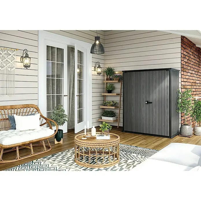 Keter Geräteschrank Signature Venetian High Store - Außenmaß inkl. Dachüberstand (B x T): 140 x 73,6 cm, Kunststoff, Grau - Dieses Bild zeigt einen grauen Outdoor-Lagerschrank auf einer Holzterrasse mit weißen Verkleidungen und dekorativen Elementen.