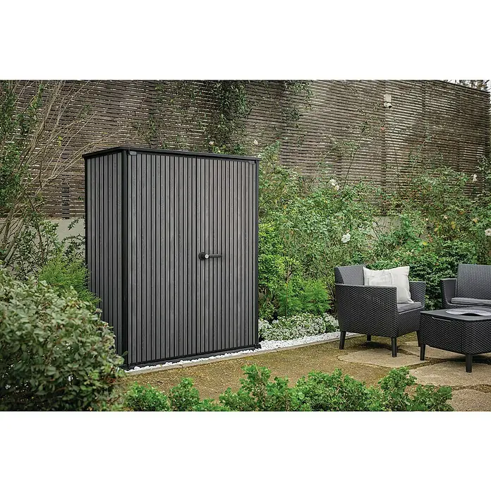 Keter Geräteschrank Signature Venetian High Store - Außenmaß inkl. Dachüberstand (B x T): 140 x 73,6 cm, Kunststoff, Grau - Ein grauer Gartenschrank mit senkrechten Latten steht auf einer Terrasse, umgeben von Pflanzen und Gartenmöbeln.