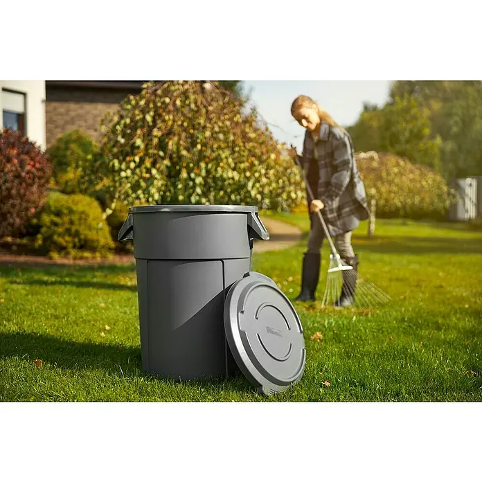 Rotho Deckel TitanGrau, Passend für: Rotho Abfalleimer Titan 85 l, Kunststoff - Grauer Gartenabfallbehälter mit abgenommenem Deckel auf Rasen vor einer Frau, die Blätter harkt, ideal für die Gartenarbeit.