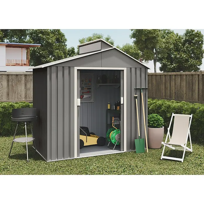 Hoggar Gerätehaus Nuuk - Außenmaß inkl. Dachüberstand (B x T): 220 x 129 cm, Stahl, Grün, Grundfläche: 2,84 m² - Gartenschuppen aus grauem Metall mit offenem Schiebetür-Eingang, flankiert von Gartengeräten. Grill und Liegestuhl stehen auf dem Rasen.