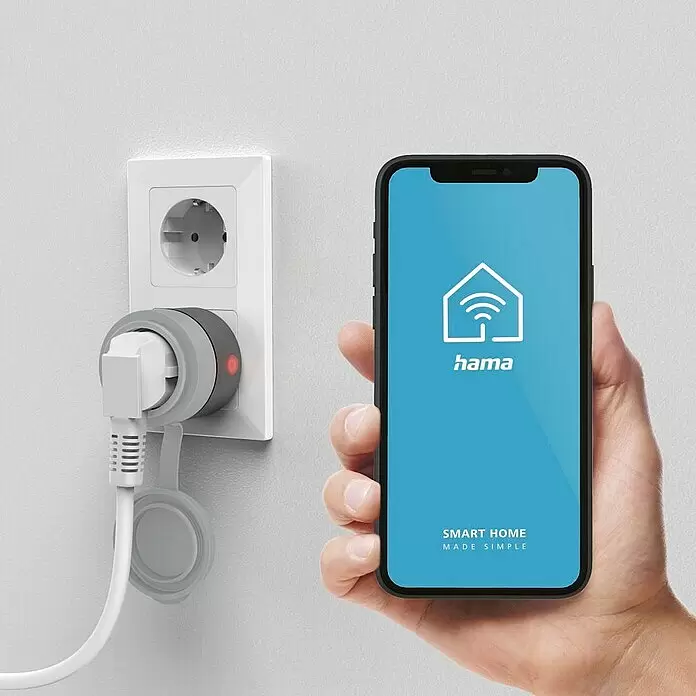 Hama Smart-Steckdose Outdoor - Außen, IP44, Grau, 2.300 W, 10 A - Weißer Smart Plug mit angeschlossenem Kabel in Steckdose, daneben Smartphone mit Hama Smart Home App.