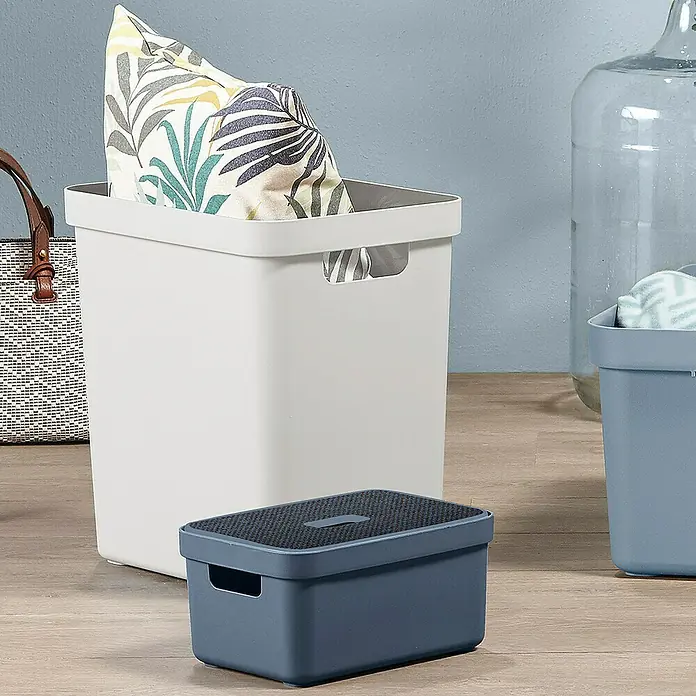Sunware Aufbewahrungsbox Sigma Home - L x B x H: 35 x 24,6 x 36,3 cm, Kunststoff, Weiß - Nahaufnahme eines weißen Aufbewahrungskorbs mit Kissen und einem blauen Trittschemel auf einem Holzboden.