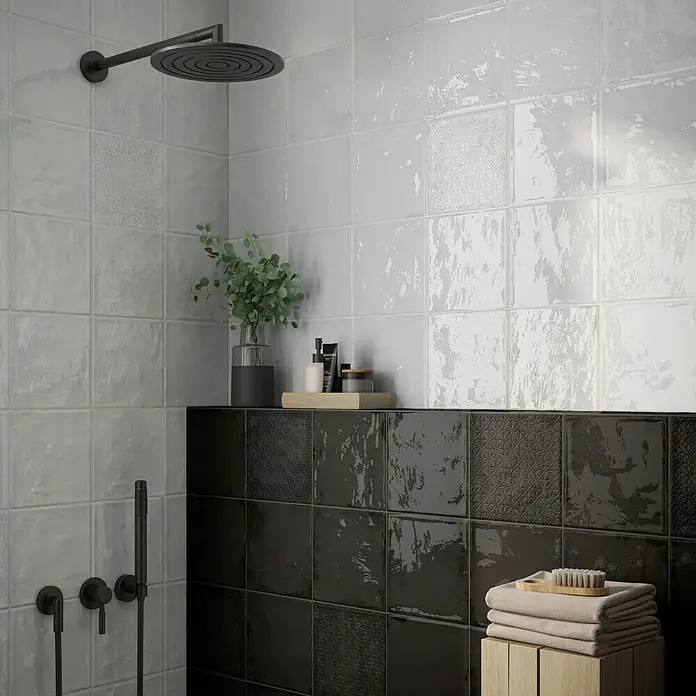 BHS Showroom Revestimiento de pared Rain - 22,3 x 22,3 cm, Cuadrado, Bianco, Brillante - Primer plano de una ducha con azulejos blancos y negros. Los azulejos tienen un acabado brillante y texturizado.