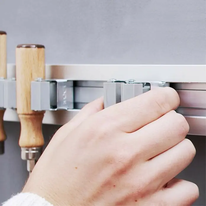 Wagner System Gerätehalter-Set mit Clips - 6 -tlg. - Nahaufnahme der Hände, die ein Werkzeug in eine Werkzeugleiste einsetzen, um Werkzeuge ordentlich und griffbereit aufzubewahren.