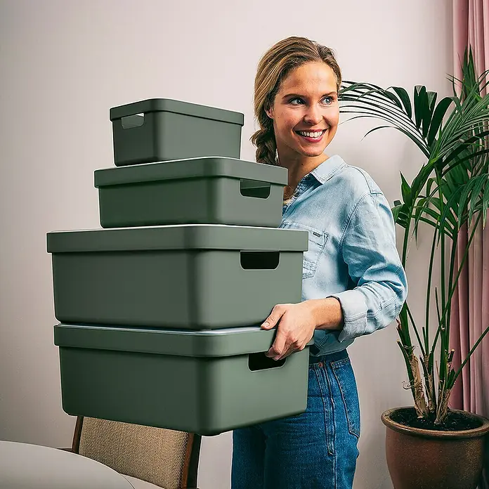 Sunware Aufbewahrungsbox Sigma Home - L x B x H: 35 x 24,6 x 12,2 cm, Kunststoff, Dunkelgrün - Eine Frau trägt einen Stapel grüner Aufbewahrungsboxen. Die Boxen sind unterschiedlich groß und haben weiße Deckel.