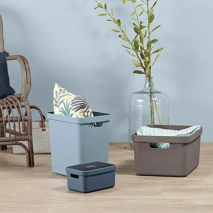 Sunware Aufbewahrungsbox Sigma Home - L x B x H: 35 x 24,6 x 36,3 cm, Kunststoff, Blaugrau - Das Bild zeigt dekorative Aufbewahrungsbehälter in verschiedenen Größen und Farben, die auf einem Holzboden angeordnet sind.