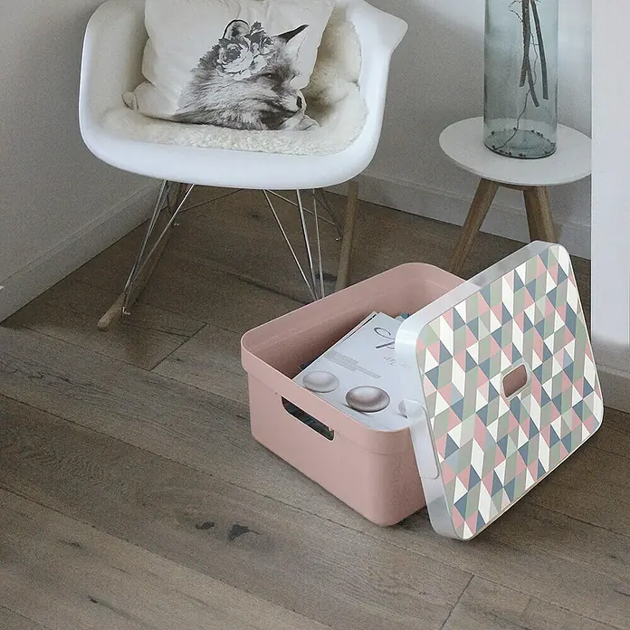 Sunware Aufbewahrungsbox Sigma Home - L x B x H: 44,5 x 34,5 x 18,3 cm, Kunststoff, Rosa - Aufbewahrungsbox aus rosa Kunststoff mit geometrischem Deckel, ideal für die Organisation. Die Box steht auf einem Holzboden neben einem Stuhl.