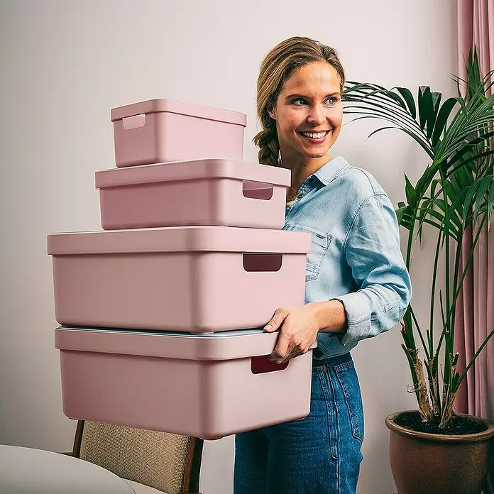 Sunware Aufbewahrungsbox Sigma Home - L x B x H: 44,5 x 34,5 x 18,3 cm, Kunststoff, Rosa - Frau trägt einen Stapel rosa Aufbewahrungsboxen.