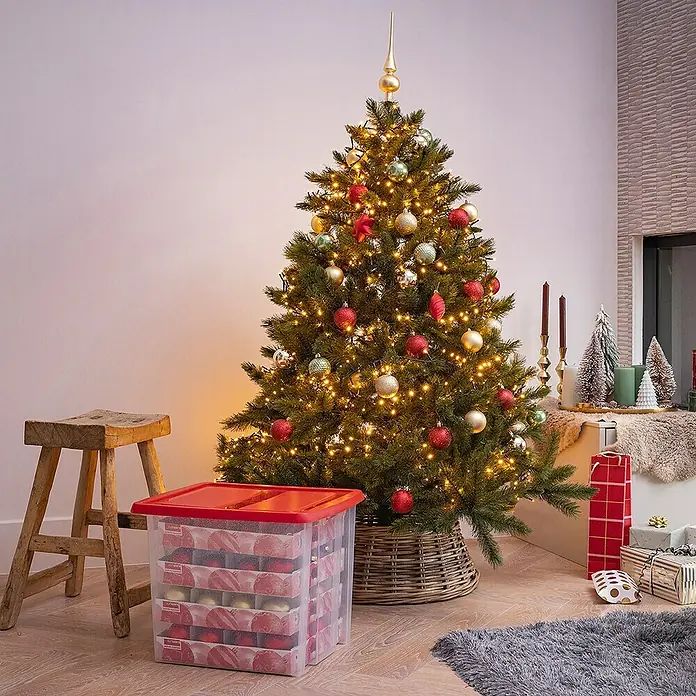 Sunware Aufbewahrungsbox Nesta für Weihnachtskugeln - Passend für: 48 Christbaumkugeln ( Ø 70 - 80 mm), L x B x H: 48 x 36,5 x 36,5 cm, Kunststoff, Transparent - Festlicher Weihnachtsbaum neben einem Lagerbehälter mit rotem Deckel, der mit Ornamenten gefüllt ist.