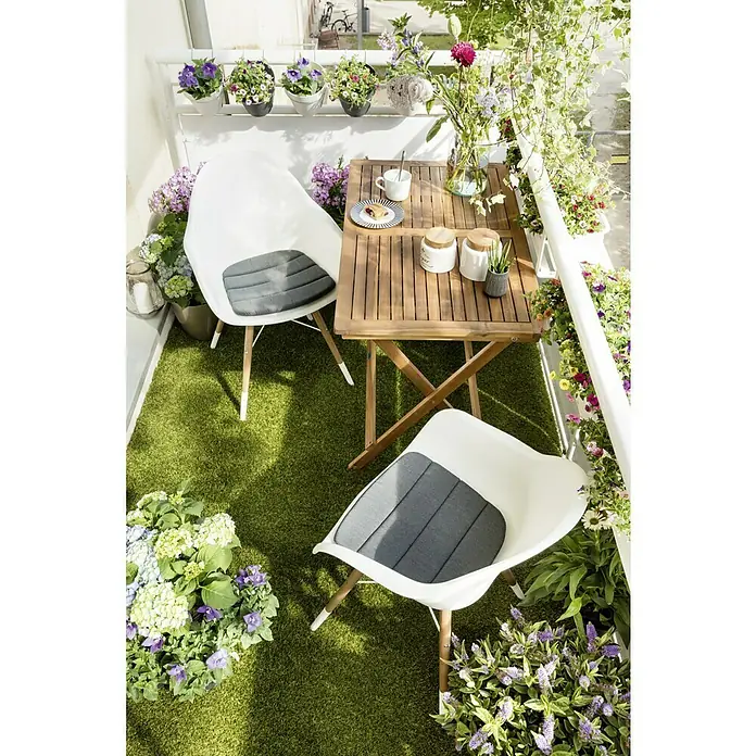 Sunfun Diana Mesa de balcón - L x An x Al: 100 x 50 x 75 cm, Acacia, Abatible, Curvado, Marrón natural - Imagen de un balcón acogedor con una mesa de madera, sillas blancas con cojines grises y arreglos florales exuberantes.