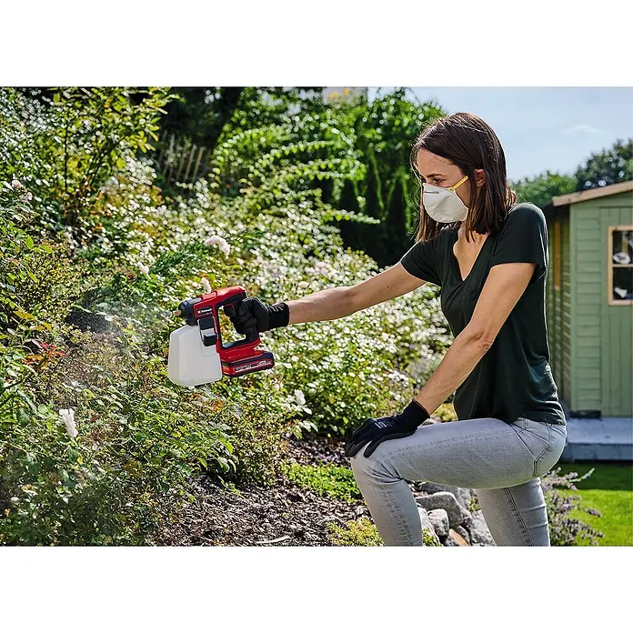 Einhell Power X-Change 18V Akku-Drucksprühgerät GE-WS 18/10 LI - 18 V, Ohne Akku, Betriebsdruck: 1,3 bar - Frau benutzt Einhell Akku-Sprühgerät zum Besprühen von Pflanzen im Garten, mit Maske und Handschuhen für Schutz.
