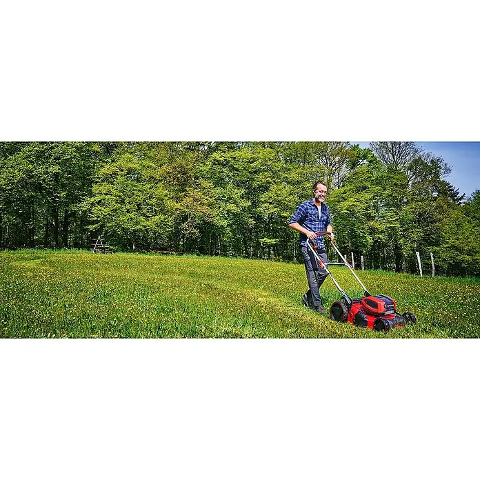 Einhell Professional Akku-Rasenmäher GP-CM 36/52 S Li BL - 36 V, 4 Akkus, 5,2 Ah, Schnittbreite: 52 cm - Ein Mann mäht den Rasen mit einem roten Einhell Rasenmäher in einem üppigen Garten mit Bäumen im Hintergrund.