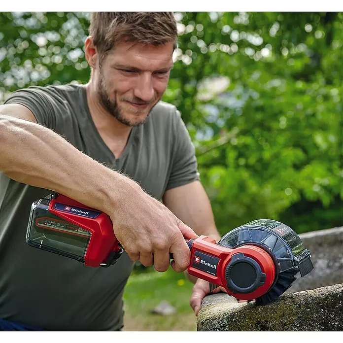 Einhell Power X-Change 18V Akku-Reinigungsbürste Picobella 18/90 - 18 V, Ohne Akku - Ein Mann benutzt eine Einhell Akku-Fugenbürste zum Reinigen einer Steinkante. Die Bürste ist rot und schwarz, mit einem transparenten Gehäuse.