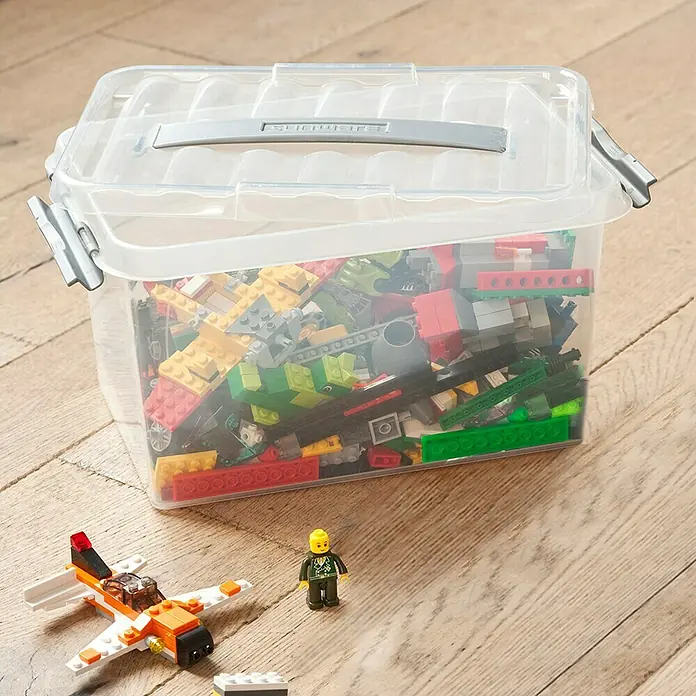Sunware Aufbewahrungsbox Q-Line - L x B x H: 30 x 20 x 14,3 cm, Kunststoff, Transparent, Farbe Griff: Schwarz - Ein transparenter Aufbewahrungsbehälter gefüllt mit bunten Legosteinen, daneben ein Spielzeugflugzeug und eine Minifigur.
