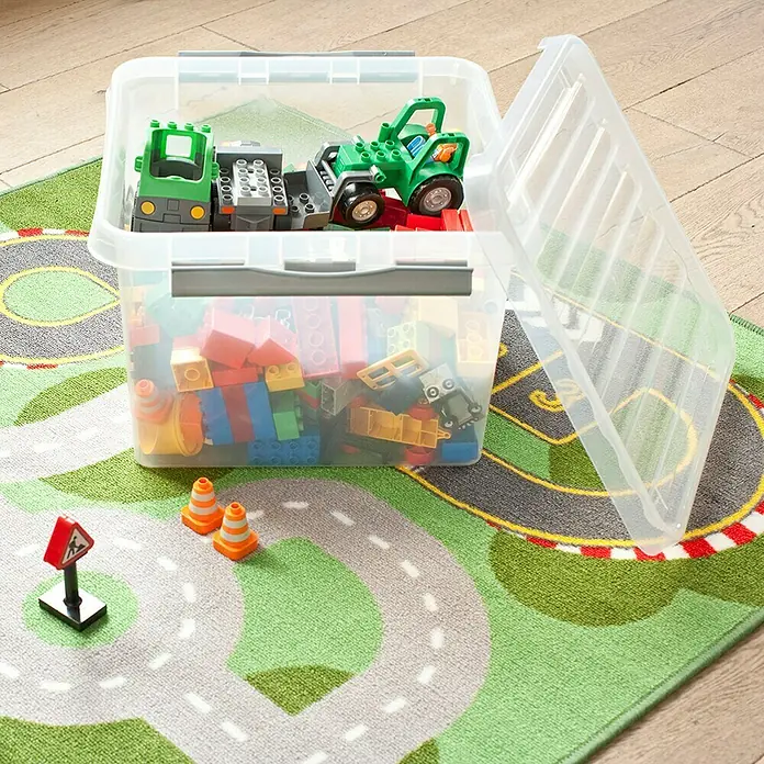 Sunware Aufbewahrungsbox Q-Line - L x B x H: 50 x 40 x 26 cm, Kunststoff, Transparent, Farbe Griff: Schwarz - Eine durchsichtige Aufbewahrungsbox mit bunten Bauklötzen und Spielzeugautos auf einem Spielteppich mit Straßenmuster.