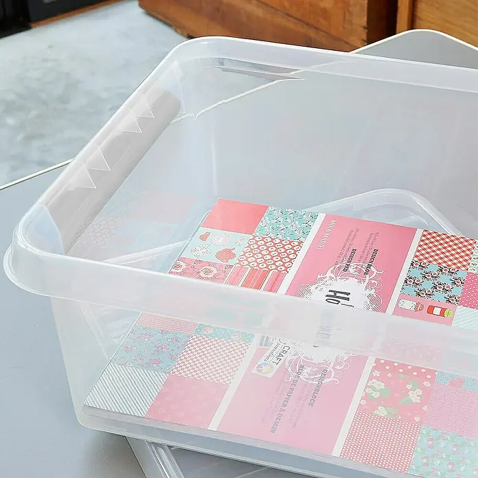 Sunware Aufbewahrungsbox Q-Line - L x B x H: 40 x 40 x 20 cm, Kunststoff, Transparent, Farbe Griff: Schwarz - Eine durchsichtige Aufbewahrungsbox aus Kunststoff, gefüllt mit einem rosa Papierblock der Marke Craft Sensations.