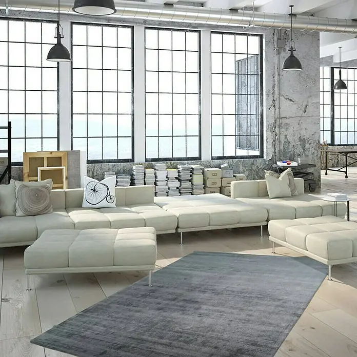Kayoom Kurzflorteppich Luxury - Mint, 150 x 80 cm, 100 % Viskose - Ein großes, helles Wohnzimmer mit einem modularen Sofa und einem grauen Teppich, beleuchtet durch moderne Hängelampen.