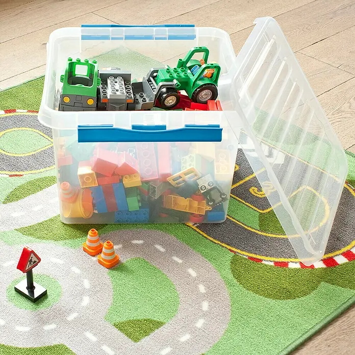 Sunware Aufbewahrungsbox Q-Line - L x B x H: 50 x 40 x 26 cm, Kunststoff, Transparent, Farbe Griff: Blau - Ein durchsichtiger Kunststoffbehälter mit Spielzeugautos und Legosteinen steht auf einem bunten Spielteppich mit Straßenmuster.