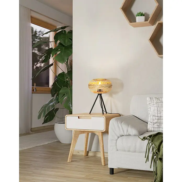 Eglo Lámpara de sobremesa Amsfield - 40 W, Ø x Al: 26 x 41 cm, Negro, Bambú, E27 - Una lámpara de mesa de ratán elegante se coloca sobre una mesa auxiliar junto a un sofá blanco, creando un ambiente cálido.