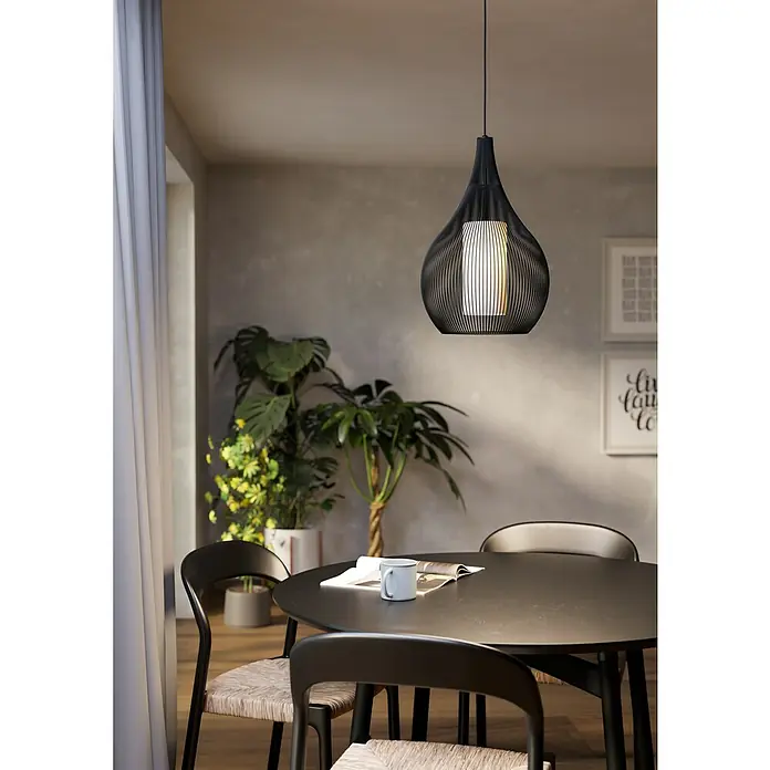 Eglo Lámpara colgante Razoni 1 - 40 W, Negro, E27 - Una lámpara colgante negra moderna cuelga sobre una mesa de comedor decorada con una taza y revistas. Proporciona un ambiente acogedor.