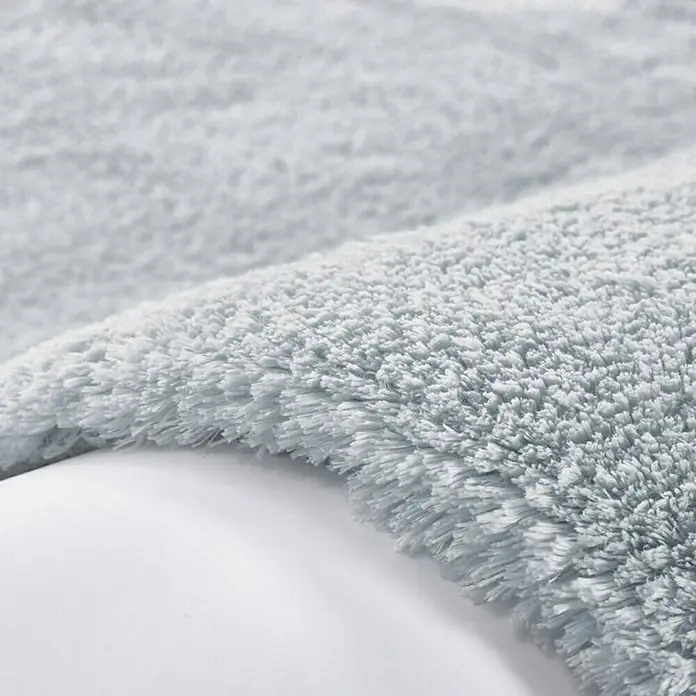 Kayoom Hochflorteppich Bali - Puderblau, 290 x 200 cm, 100 % Polyester - Nahaufnahme einer weichen, hellgrauen Badematte, die eine luxuriöse und komfortable Textur für den täglichen Gebrauch im Badezimmer bietet.
