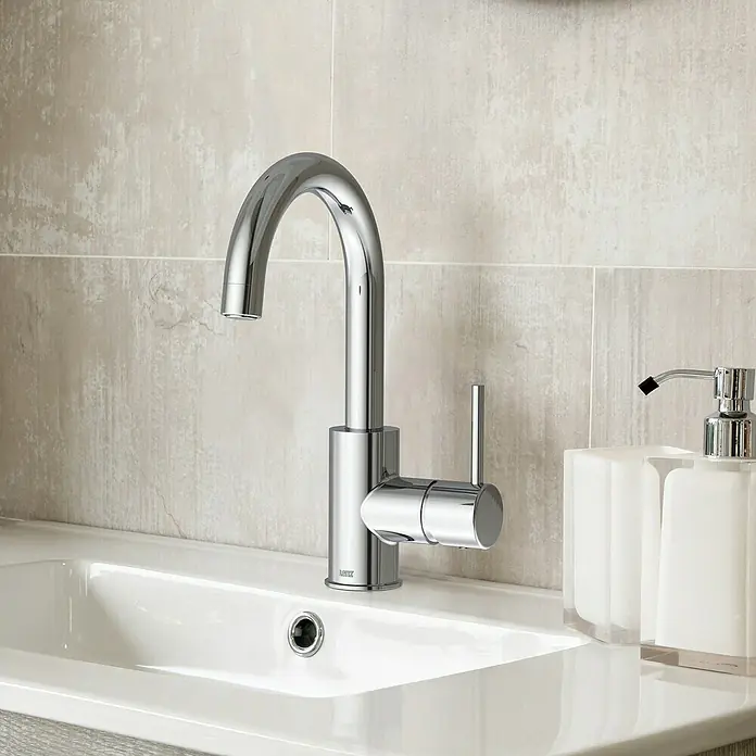 Lenz Bow Waschtischarmatur 2 - Niederdruck, Chrom, Glänzend - Nahaufnahme einer modernen Chromarmatur auf einem Waschbecken mit einer weißen Seifenspenderflasche.