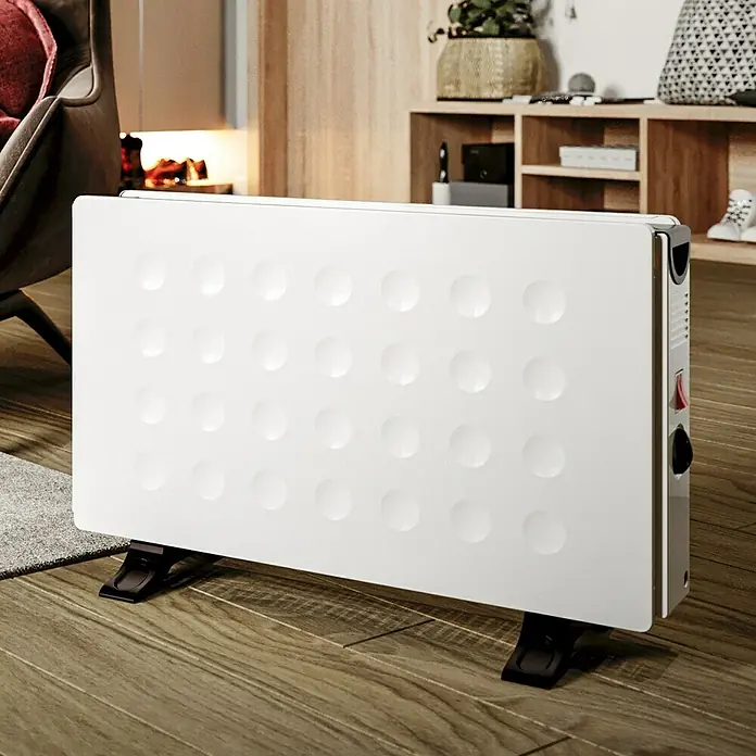 Voltomat HEATING Konvektorheizung Dubbe - 2.000 W, Raumgröße bis ca. 20 m², Weiß - Weißer Heizkörper mit gepunkteter Oberfläche und Bedienfeld an der Seite, steht auf einem Holzboden.