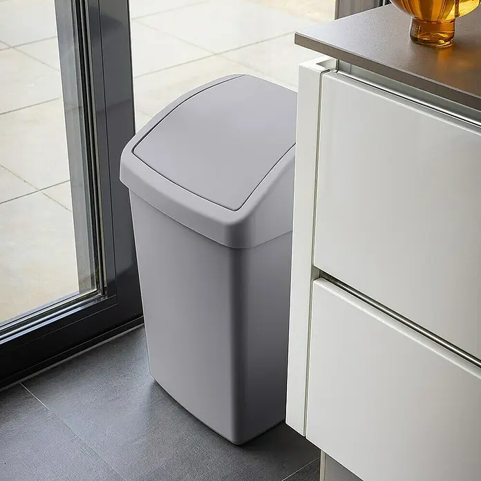 Sunware Schwingdeckeleimer Delta - 50 l, Kunststoff, Grau - Grauer Schwingdeckeleimer neben einem weißen Schrank. Der Schwingdeckeleimer ist eckig und hat einen grauen Deckel.