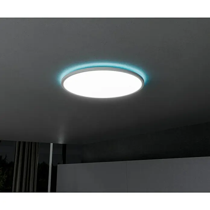 Brilliant LED-Deckenleuchte rund Tanida rund - 22 W, Ø x H: 42 x 2,6 cm, Weiß, Kaltweiß - Nahaufnahme einer runden Deckenleuchte mit blauer Hintergrundbeleuchtung, die modernes Design und stimmungsvolle Beleuchtung vereint.