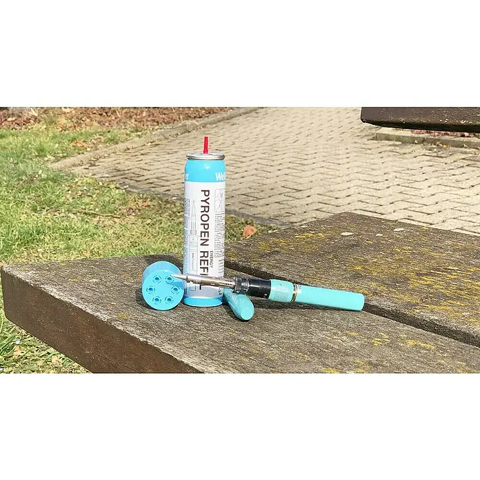 Weller Gas-Nachfüllkartusche T0051616090 - 1 Stk. - Ein Pyropen Refill Kanister und ein Gaslötkolben mit Zubehör liegen auf einer Holzbank im Freien.