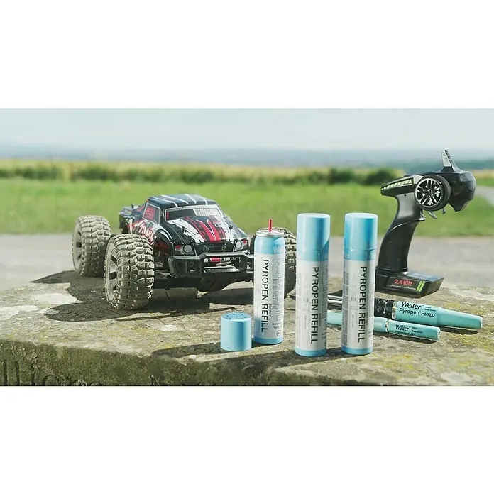 Weller Gas-Nachfüllkartusche T0051616090 - 1 Stk. - Nahaufnahme eines RC-Autos, eines Controllers und Weller Pyropen Piezo-Nachfüllungen, die auf einer Betonoberfläche platziert sind.