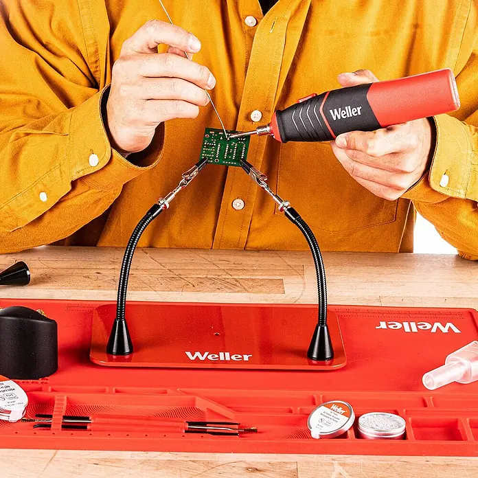 Weller Lötkolben WLIBAK8 - Arbeitstemperatur: 485 °C - Nahaufnahme einer Person, die mit einem Weller-Lötwerkzeug an einer elektronischen Platine arbeitet, professionelle Elektronikreparatur.
